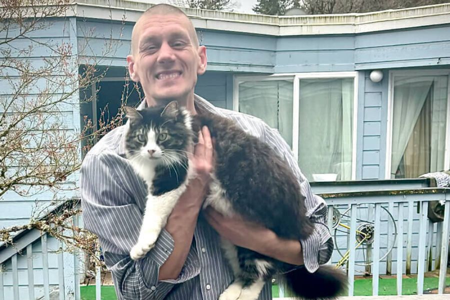 A man with his pet cat in front of a living facility